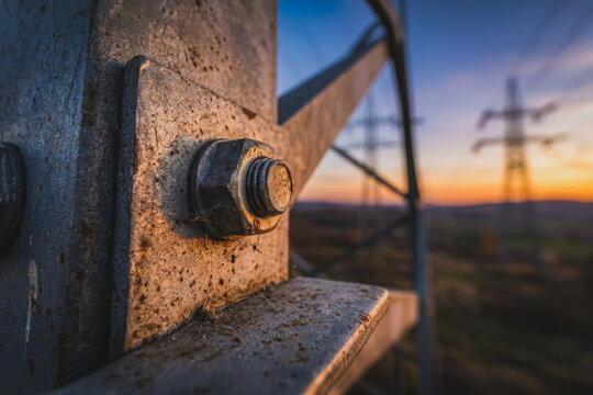 Steel bolt and nut on a metal pylon at sunset