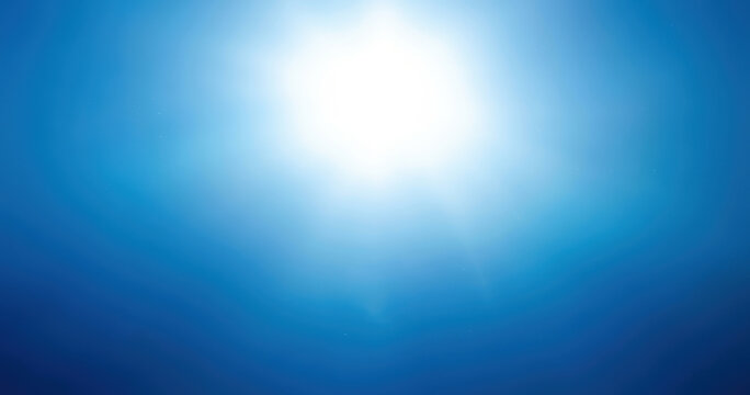 Bright white sun flare centered in a clear blue sky, soft radial light gradient fading into deep azure at the corners