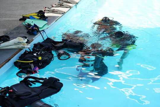 A professional diver and a novice practice diving in a pool.