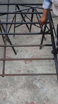 Young Man Painting Rusted Iron Structure with Paintbrush