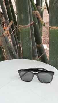 Black Sunglasses on White Table Beside Green Bamboo Stalks