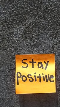 Bright Sticky Note on Grey Wall with Phrase Stay Positive