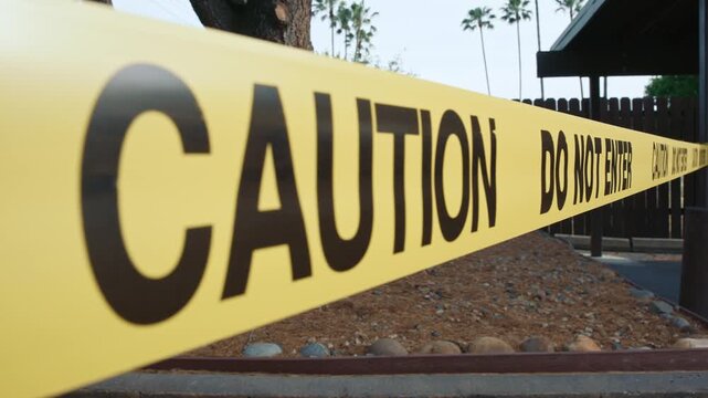 Yellow caution tape do not enter close up diagonal blocking unsafe area showing restricted access and control of hazardous outdoor zone