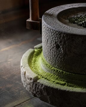 Matcha stone mill grinding tencha in a dim Japanese tea workshop