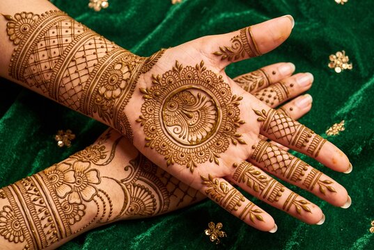 Beautiful henna tattoo design on brides hands on a green background