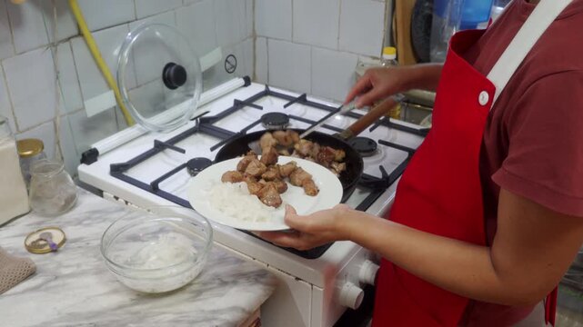 Cooking plating food, in kitchen, with pan, rice, plate, spatula, from a first-person perspective perspective, with red, white accents, and focused mood, showing the main action and place clearly.