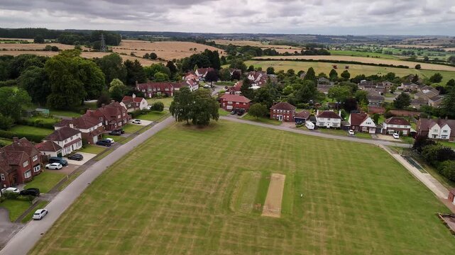 Aerial View of Village Cricket Pitch and Houses with Countryside Backdrop in Northamptonshire