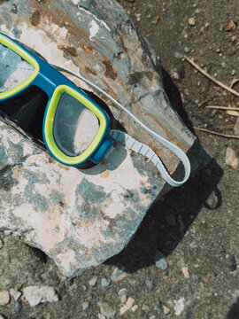 Close-up of snorkeling mask on stone by lake, outdoor summer swimming gear.