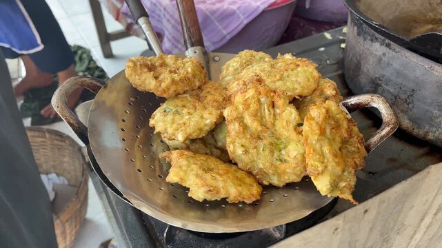 Lifting crispy vegetable stuffed tofu on a slotted strainer over frying wok