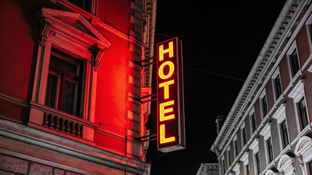 Moody neon-lit hotel sign glowing against urban night architecture