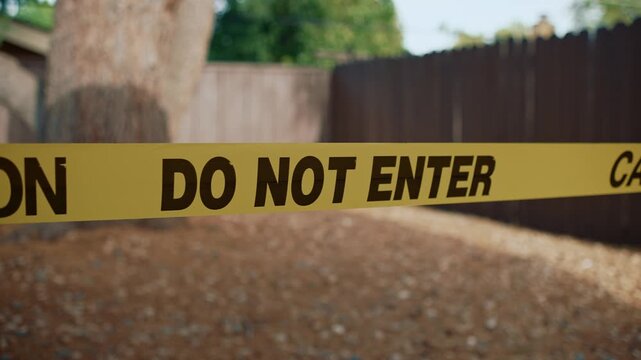 Yellow caution tape do not enter in focus blocking unsafe area showing restricted access and control of hazardous outdoor zone