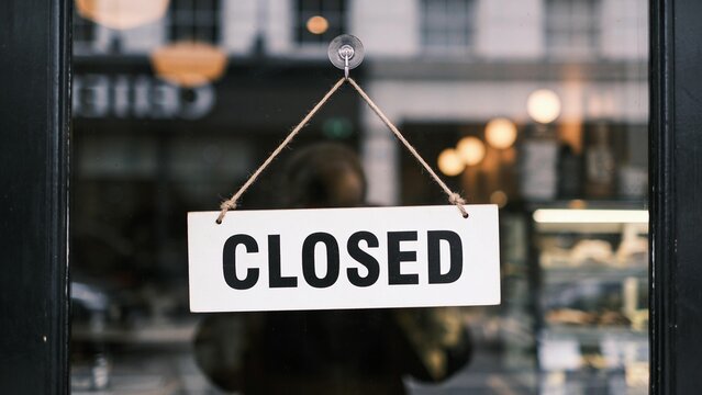 Closed business sign hanging outside modern storefront with blurred interior