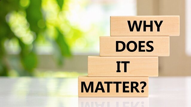 Minimalist wooden blocks spelling why does it matter against blurred green background