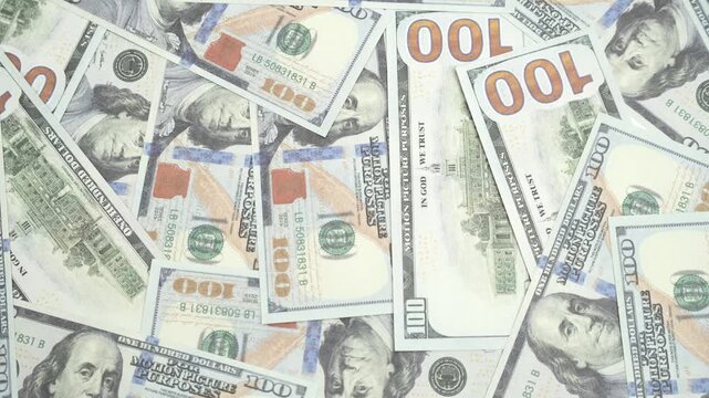 Flat lay top view of scattered hundred US dollar bills filling the frame as background, money elements transition and stopmotion, 4K footage motion