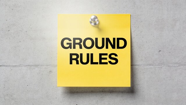 Bright yellow sticky note displaying bold ground rules text on plain concrete wall