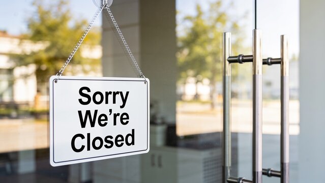 Closed business sign hanging outside modern glass storefront during daylight