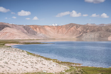 Clear-water rivers and lakes in a mountain valley, pastures and green grassy fields set against mountain ranges and snow-capped, glacier-clad peaks—a scenic landscape background © Denis