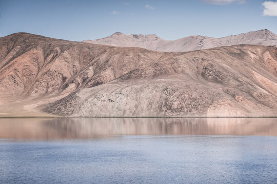Clear-water rivers and lakes in a mountain valley, pastures and green grassy fields set against mountain ranges and snow-capped, glacier-clad peaks&mdash;a scenic landscape background