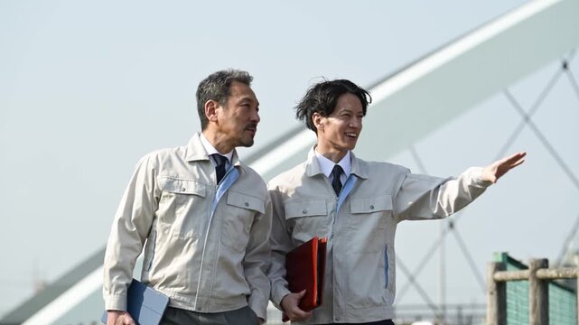橋梁工事の現場で指差しをしながら打ち合わせを行う30代と50代の作業員