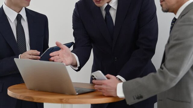 ノートパソコンとタブレットを使って打ち合わせを行う30代と50代の日本人ビジネスマン