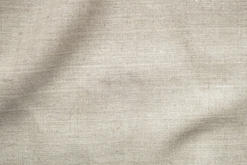 Fototapeta premium Natural beige linen fabric texture with soft shadow and copy space. Organic textile background ideal for branding, skincare, packaging, lifestyle and minimalist design.