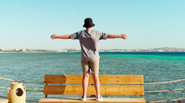 A teenage boy looks with delight at the turquoise sea bay of SAHL Hasheesh in Egypt. A happy child on summer vacation at a resort.