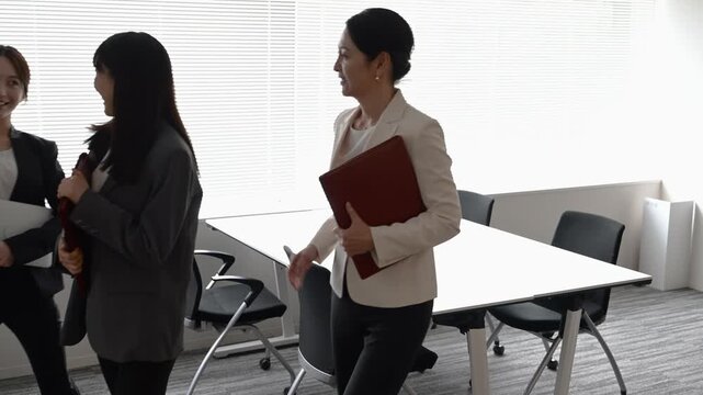 会議室で歩きながら打ち合わせを行う20代から40代の日本人ビジネスパーソン3人