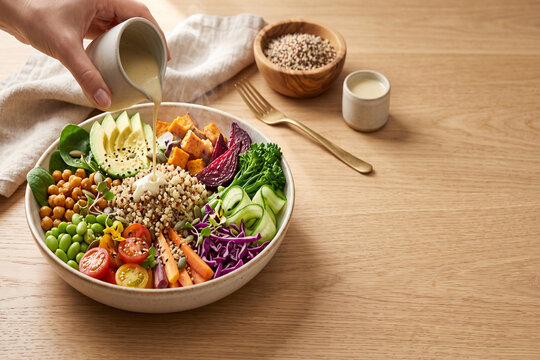 Quinoa buddha bowl with avocado, sweet potato, chickpeas, tahini dressing, and hand-portioned dressing