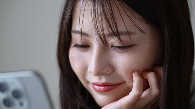 スマートフォンを見ながら微笑む20代日本人女性のクローズアップ