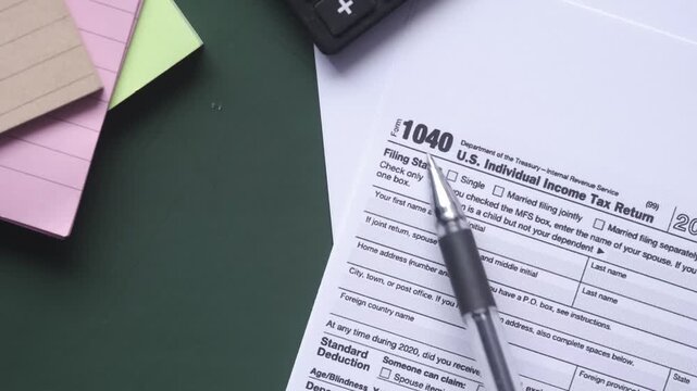 Close up of 1040 tax form with pen and sticky notes on desk motion