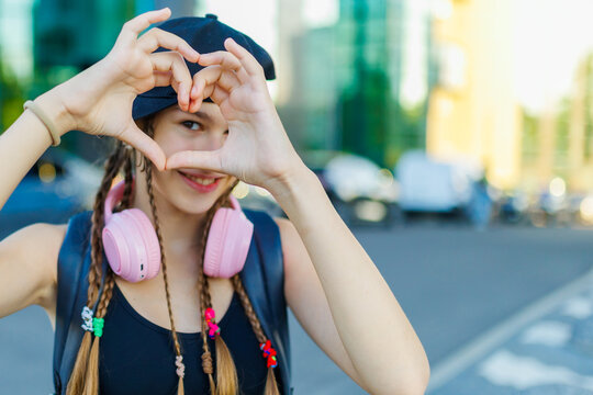 Generation Alpha, Close up of happy teenager making heart shape with hands outside.