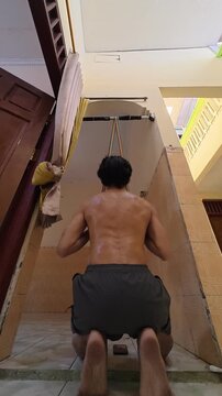 Rear view of man doing seated resistance band lat pulldown exercise at home