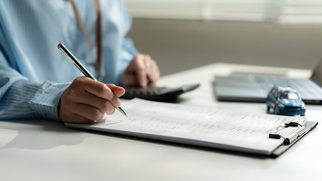 Business woman completing a car insurance application with financial documents, calculator, and vehicle model, representing policy registration, underwriting, claims processing, and risk assessment.