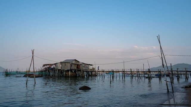Timelapse of a traditional wooden fishing stilt house over calm sea water during late afternoon in Vietnam.