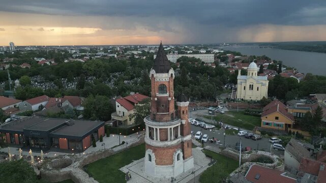 Cinematic aerial footage of Gardos Tower at dusk with dramatic cloudy sky and distant lightning over the Danube River, Zemun, Belgrade, Serbia.