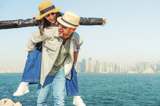 Multiracial beautiful young happy couple of lovers travelers - Multiethnic tourists travelling in middle east and visiting gulf country of Qatar. Doha corniche.Concepts tourism, couple travel lifestyle