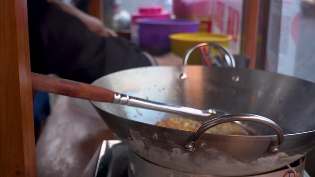 A local street food vendor frying a traditional Indonesian egg and tofu dish in a large wok at an authentic stall, showcasing regional culinary heritage and preparation.