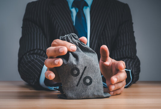 Business professional holding money bag with interest rate symbol. Personal finance, lending, investment strategy, financial planning, risk management, economic policy and wealth management decisions.
