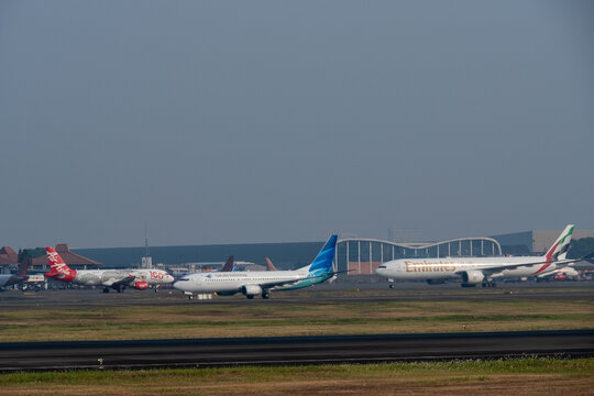 Jakarta, Indonesia - July 15, 2026: Garuda Indonesia Boeing 737-800 accelerates for takeoff while AirAsia and Emirates aircraft taxi on tarmac at Soekarno-Hatta International Airport.