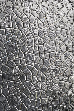 A close up shot of a grey textured glass panel featuring a geometric mosaic pattern with striped and dotted section