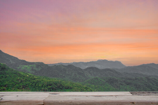 Wooden plank tabletop for product display with mountain view at sunset. 