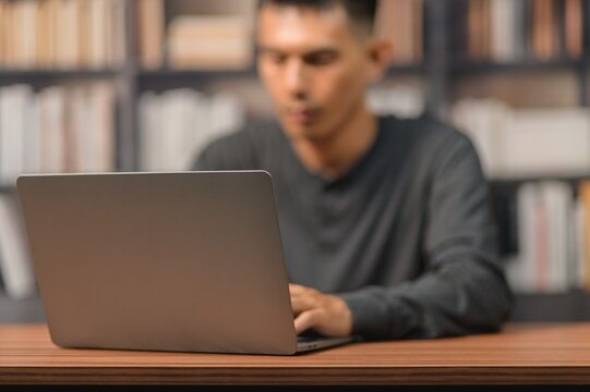 Young Man Working on Laptop at Desk in Modern Home Office Setting