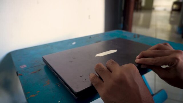 A person closing a laptop computer on a desk, capturing the end of a workday, office routine, and digital technology use for modern remote business tasks.