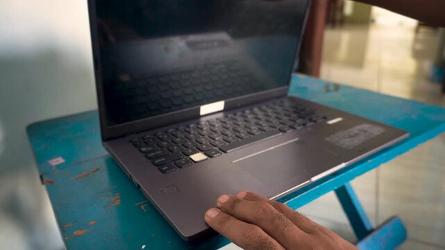 A person turning on a laptop computer on a desk, capturing the start of a workday, office routine, and digital technology use for modern remote business tasks.