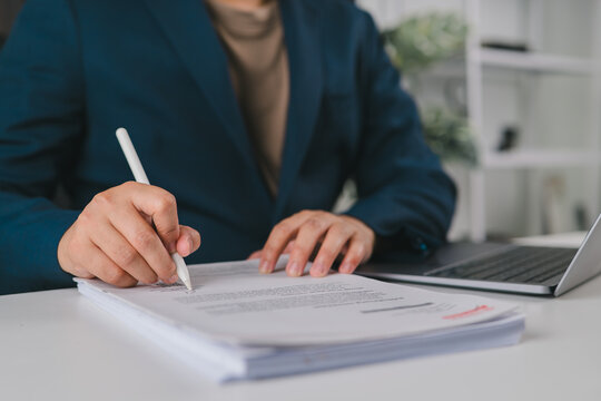 Businessman reviewing financial documents, tax paperwork, file folders, and business records on a laptop, representing accounting, document management, compliance, and office administration.