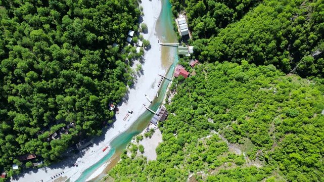 High to low shot, following the Shala River, Albania. Showing the hotels, river and riverbed. Shot on a 4k at 60 fps on a DJI Mini 3 Pro in D-Log Film Colorgraded