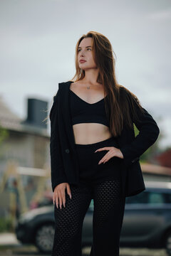 Beautiful young woman posing in stylish black outfit on a city street