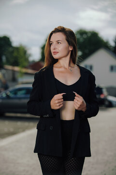 Elegant woman in black blazer looking away posing outdoors with flash lighting