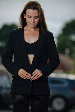 Confident businesswoman in fashionable dark suit posing on city street