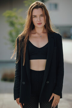 Beautiful woman in black blazer and crop top posing in natural daylight